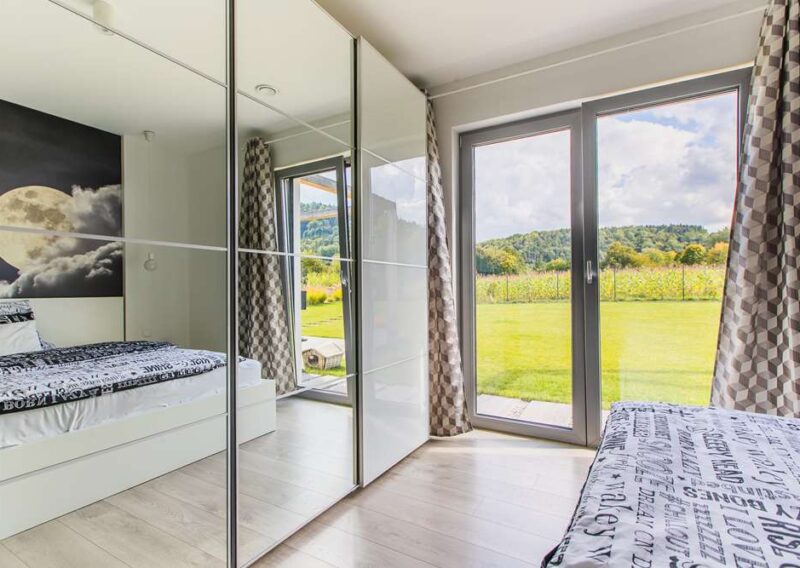 sypialnia domu prefabrykowanego z dużą szafą z lustrzanymi drzwiami